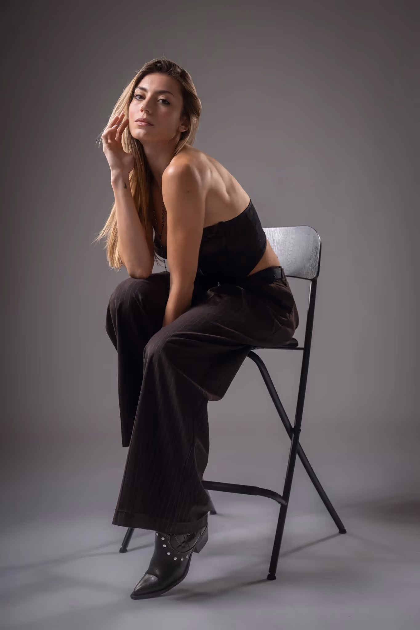 Donna bionda seduta su uno sgabello in studio