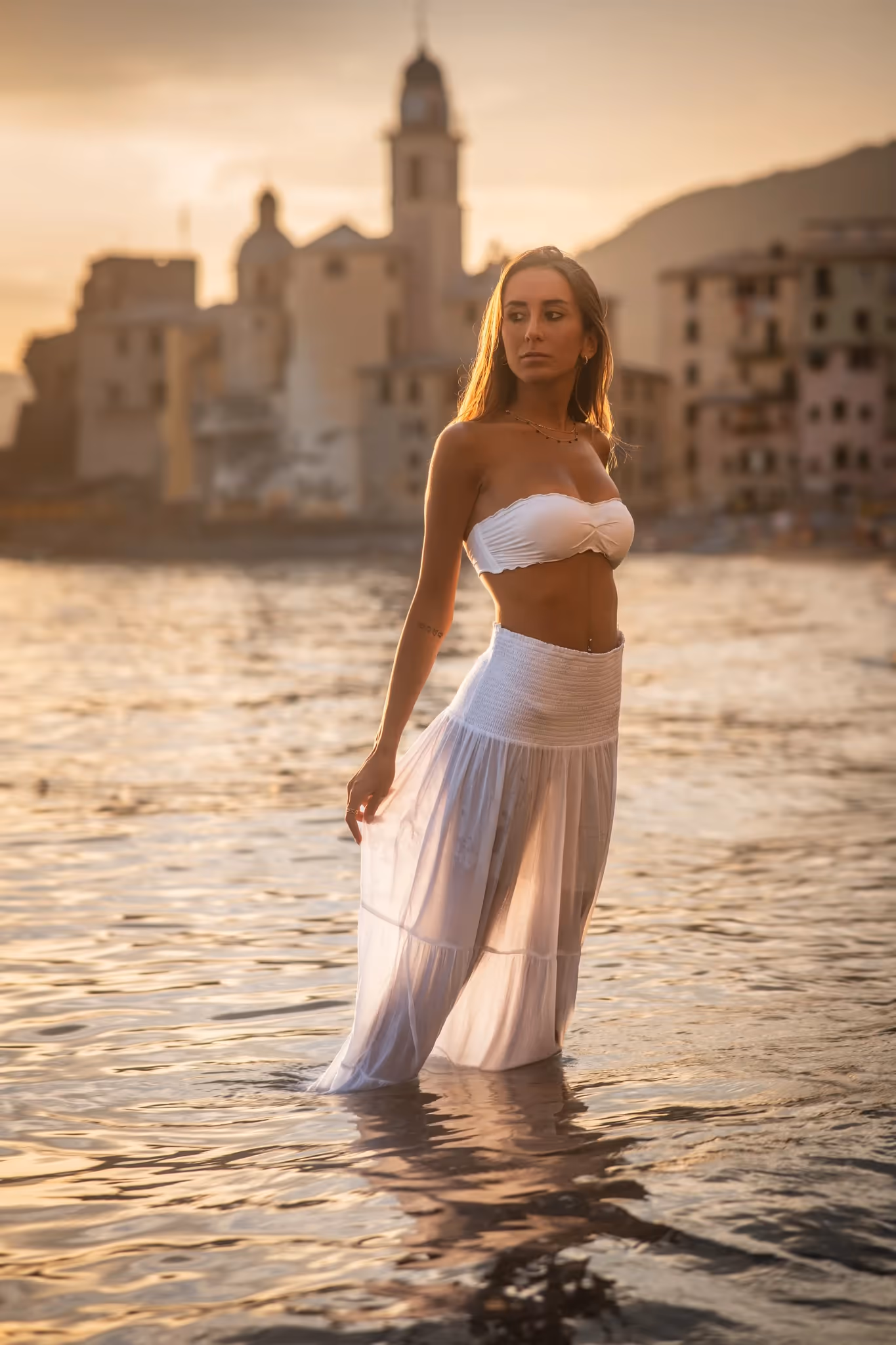 Modella in top bianco e gonna rossa davanti a una parete